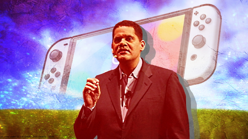 Reggie Fils-Aime speaking at a conference. Nintendo Switch and green field with cloudy skies in the background. 