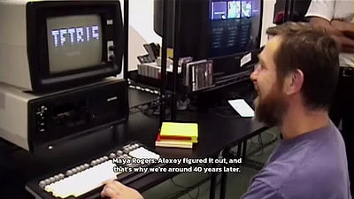 A man sits in front of an old computer playing Tetris